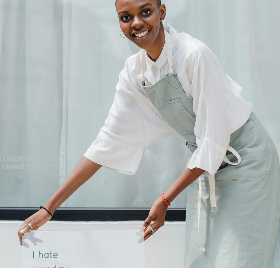 Happy black female worker setting signboard outside cafeteria